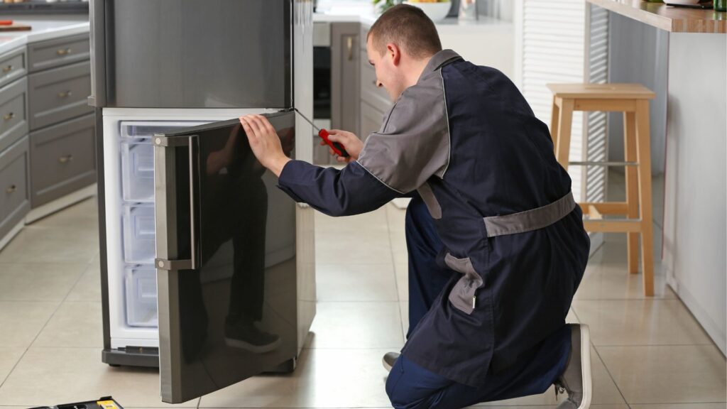 Technician inspecting a refrigerator door hinge for appliance repair in College Park MD