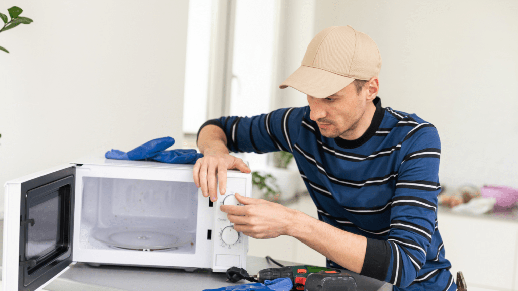 Technician inspecting microwave control knobs for appliance repair in Mount Airy MD