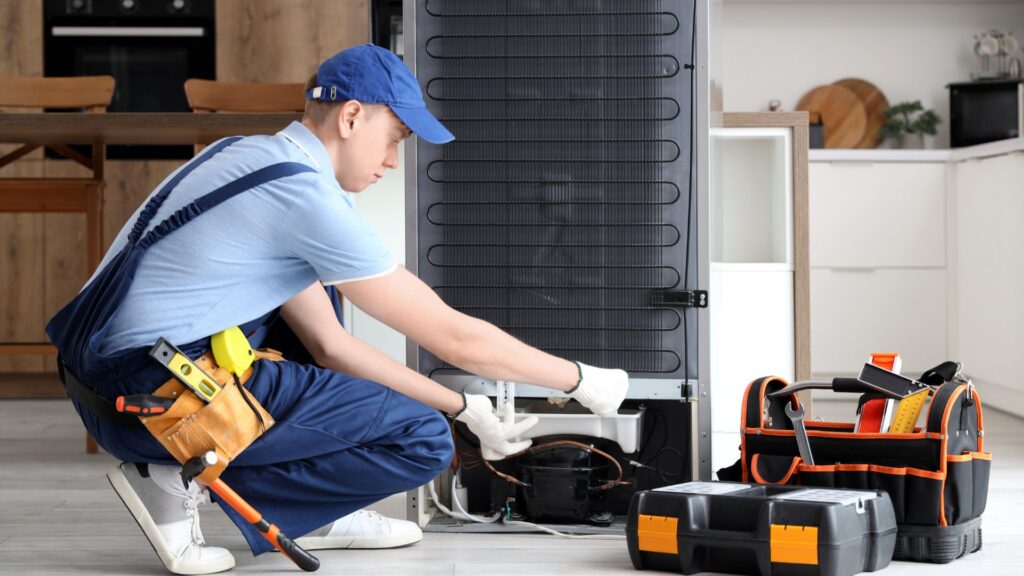 Technician repairing a refrigerator in a kitchen for appliance repair in Friendship Heights DC