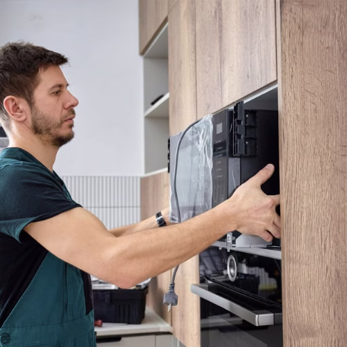 Technician installing a built-in microwave oven for appliance repair in Fair Oaks VA