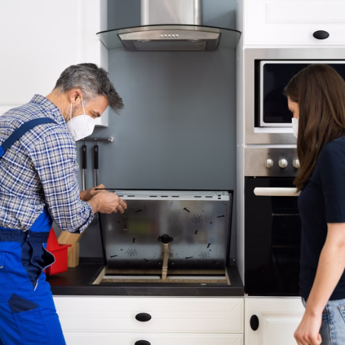 Technician inspecting an electric cooktop for appliance repair in Clarksburg MD