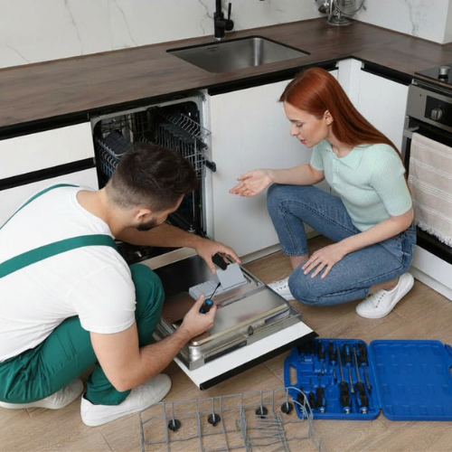 Technician explaining a dishwasher diagnosis to a homeowner in the kitchen for appliance repair in Reston VA