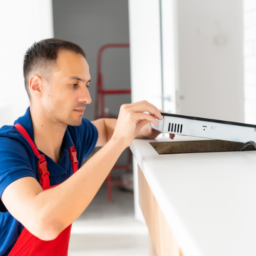Technician inspecting a cooktop for appliance repair in Tenleytown DC